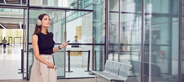    A male wearing the Sony WH-1000XM3 walking into a building with glass walls